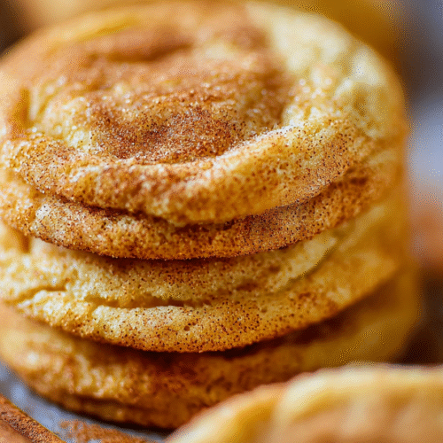 Soft and chewy Snickerdoodle cookies rolled in cinnamon sugar on a baking tray
