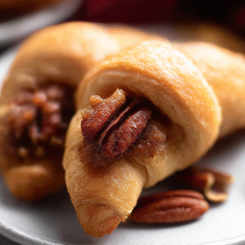 Golden pecan pie crescents drizzled with caramel sauce on a white plate