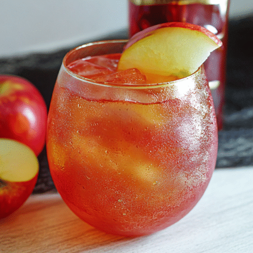 Halloween Poison Apple Punch cocktail with golden shimmer and apple garnish