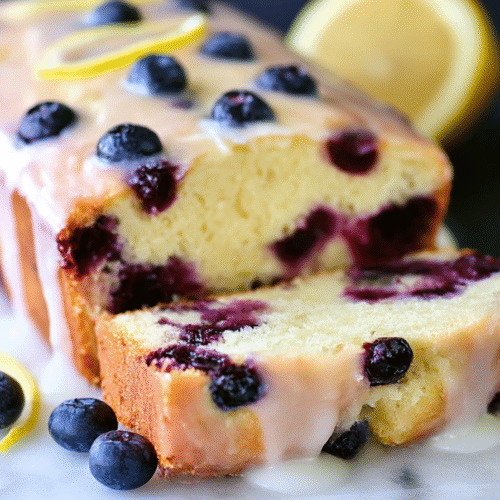 Freshly baked moist lemon blueberry bread with lemon glaze and blueberries on top
