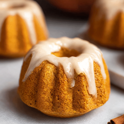 Mini pumpkin bundt cakes drizzled with maple glaze on a rustic table