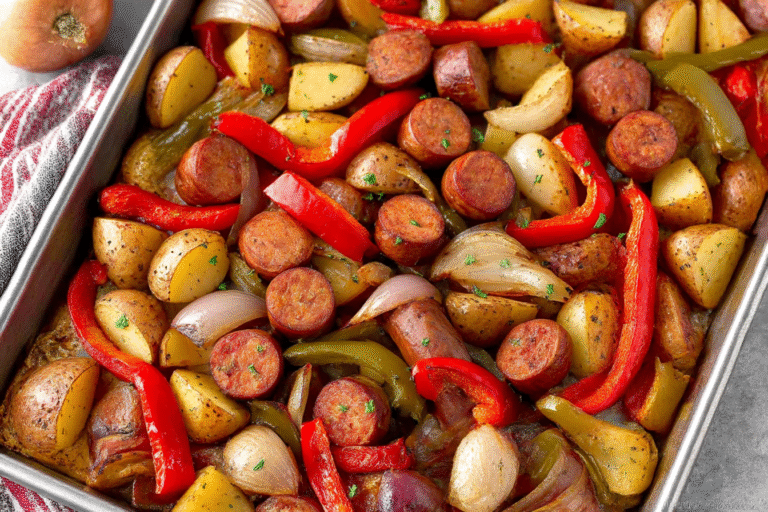 One-pan roasted sausages with peppers, onions, and potatoes on a baking sheet